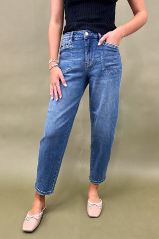 Person wearing blue jeans and a black top on a beige background