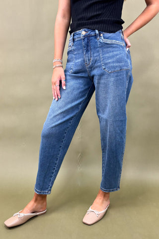 Person wearing blue jeans and a black top on a beige background