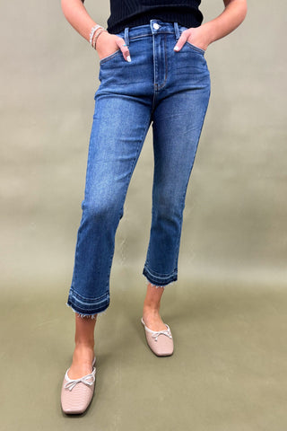 Person wearing blue jeans and light pink shoes on a plain background