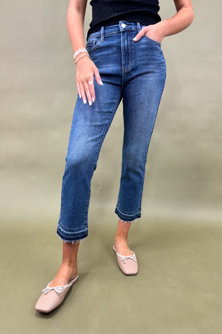 Person wearing blue jeans and pink shoes on a green background