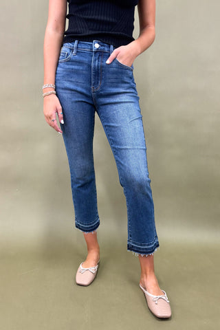 Person wearing blue jeans and a black top on a plain background