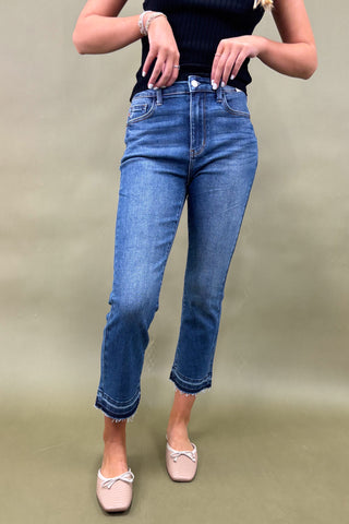 Person wearing blue jeans and a black top on a beige background