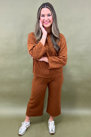 Woman wearing a brown outfit against a green background