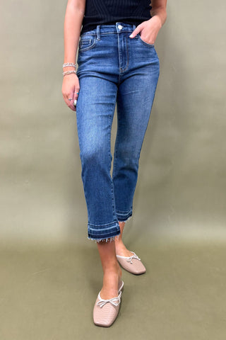 Person wearing blue jeans and beige shoes on a plain background