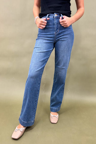 Person wearing blue jeans on a beige background