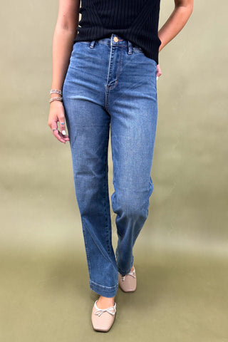 Person wearing blue jeans and a black top on a beige background