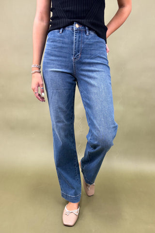 Person wearing blue jeans on a beige background