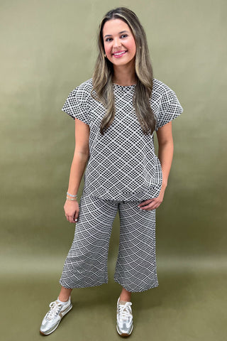 Woman wearing a black and white patterned outfit on a green background
