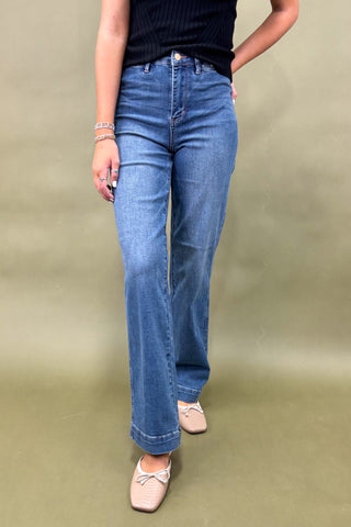 Person wearing blue jeans on a plain background