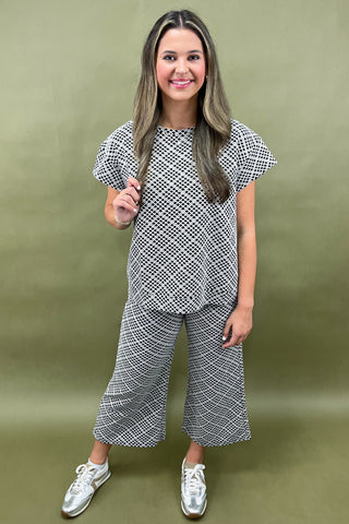 Woman wearing a black and white checkered outfit against a green background