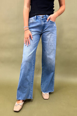 Person wearing blue flared jeans on a beige background
