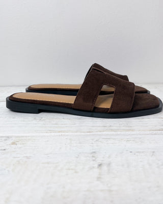 Brown sandal with a black sole on a light gray background