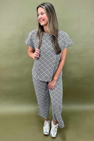 Woman wearing a patterned outfit against a green background