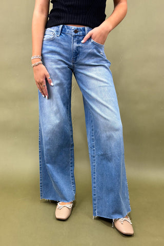 Person wearing blue jeans and a black top on a green background