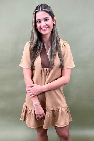 Woman wearing a beige dress against a plain background