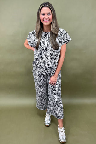 Woman wearing a black and white patterned outfit against a green background