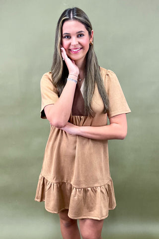 Woman wearing a beige dress against a green background