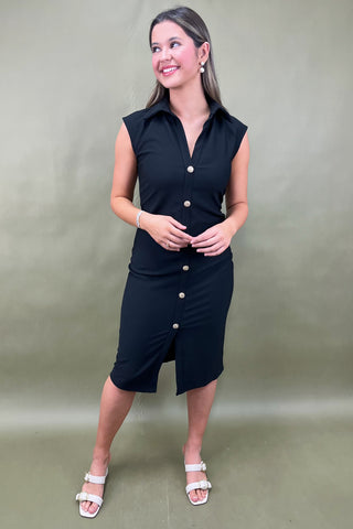 Woman wearing a black sleeveless dress with buttons against a plain background