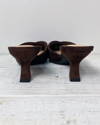 Pair of brown suede shoes on a light wooden floor with a white wall background