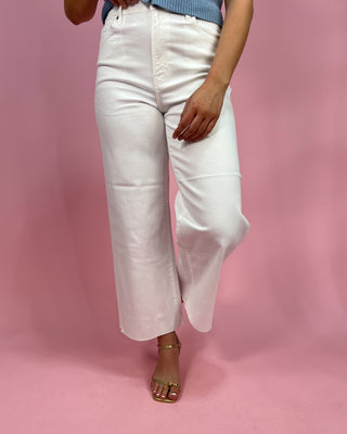 Person wearing white pants on a pink background