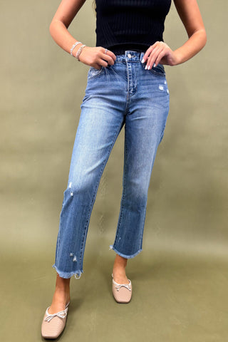 Person wearing blue jeans and a black top on a green background