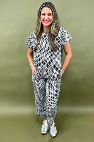 Woman wearing a black and white patterned outfit against a green background