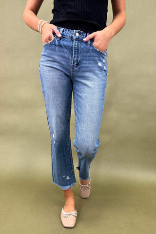 Person wearing blue jeans with a plain background