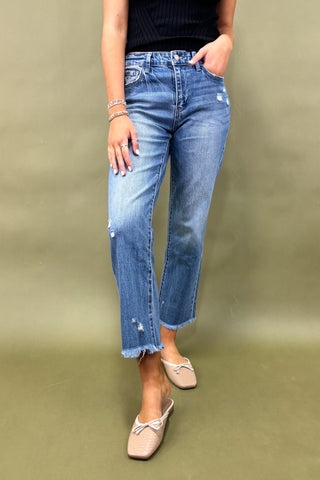 Person wearing blue jeans and beige shoes on a green background