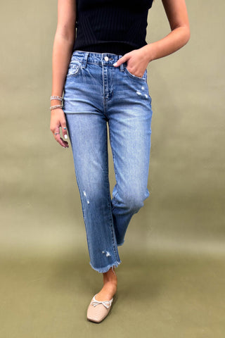 Person wearing blue jeans and a black top on a beige background