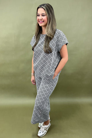 Woman wearing a black and white patterned outfit against a green background