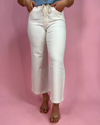 Person wearing white jeans on a pink background