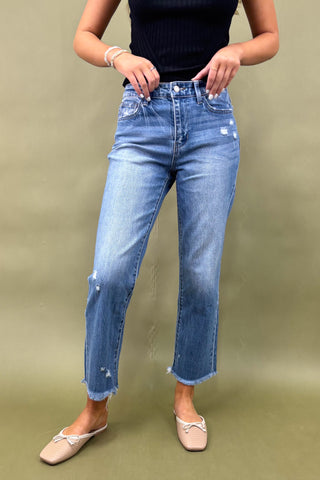 Person wearing blue jeans and a black top on a green background
