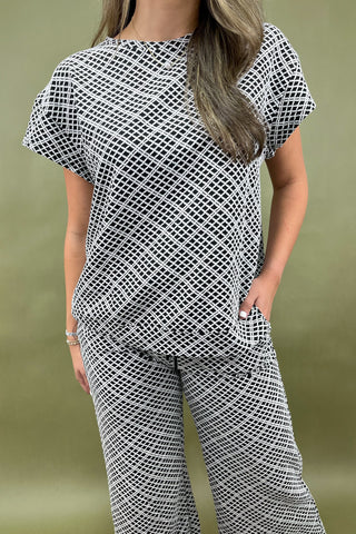 Person wearing a black and white patterned outfit against a green background