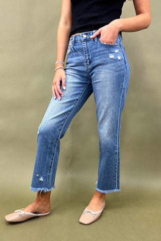 Person wearing blue jeans and a black top on a green background