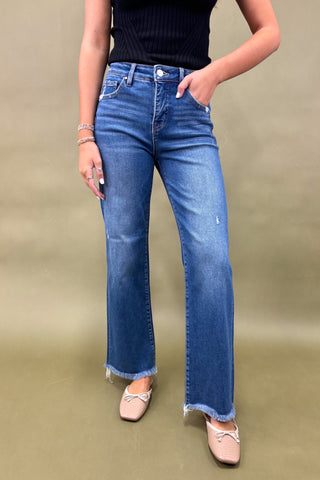 Person wearing blue jeans and a black top on a beige background