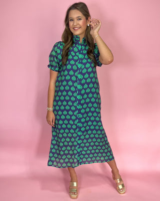 Woman wearing a green patterned dress against a pink background