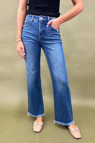 Person wearing blue jeans and a black top on a green background