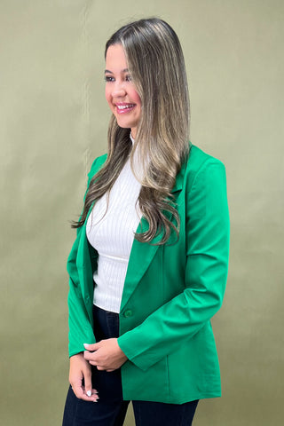 Woman wearing a green blazer over a white top on a beige background
