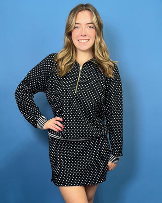 Black and white polka dot quarter zip top with gold zipper, striped trim, long sleeves, and relaxed fit.