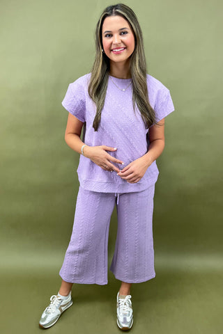 Woman wearing a purple outfit standing against a green background