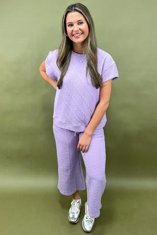 Woman wearing a purple outfit against a green background
