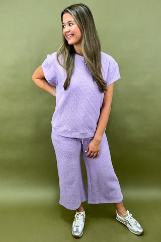 Woman wearing a purple outfit standing against a green background