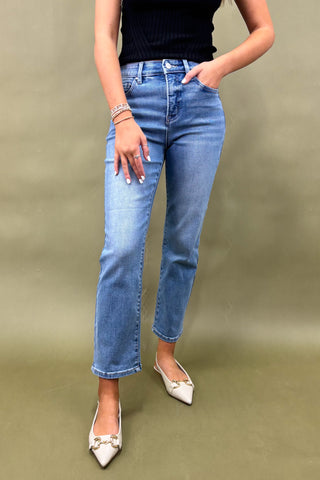 Person wearing blue jeans and white shoes on a plain background