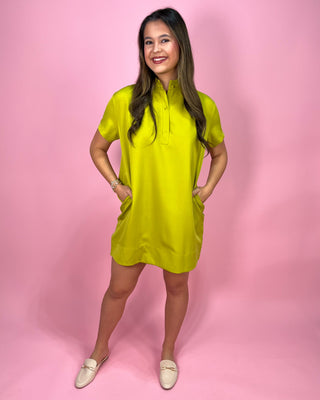 Woman wearing a bright green dress against a pink background