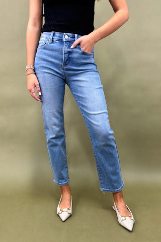 Person wearing blue jeans and white shoes on a green background