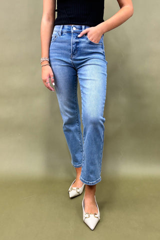 Person wearing blue jeans and white shoes on a plain background