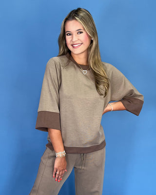 Woman wearing a brown outfit against a blue background