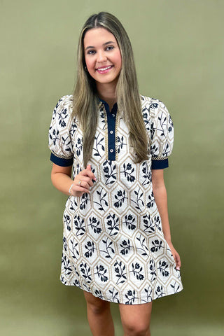 Woman wearing a white dress with black floral patterns against a green background