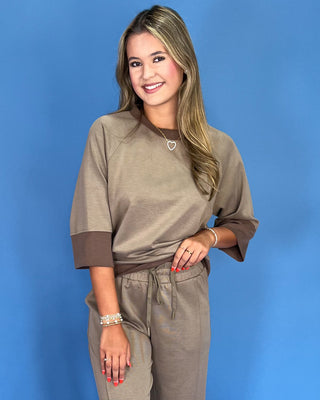 Woman wearing a brown outfit against a blue background