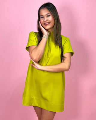 Woman wearing a bright green dress against a pink background